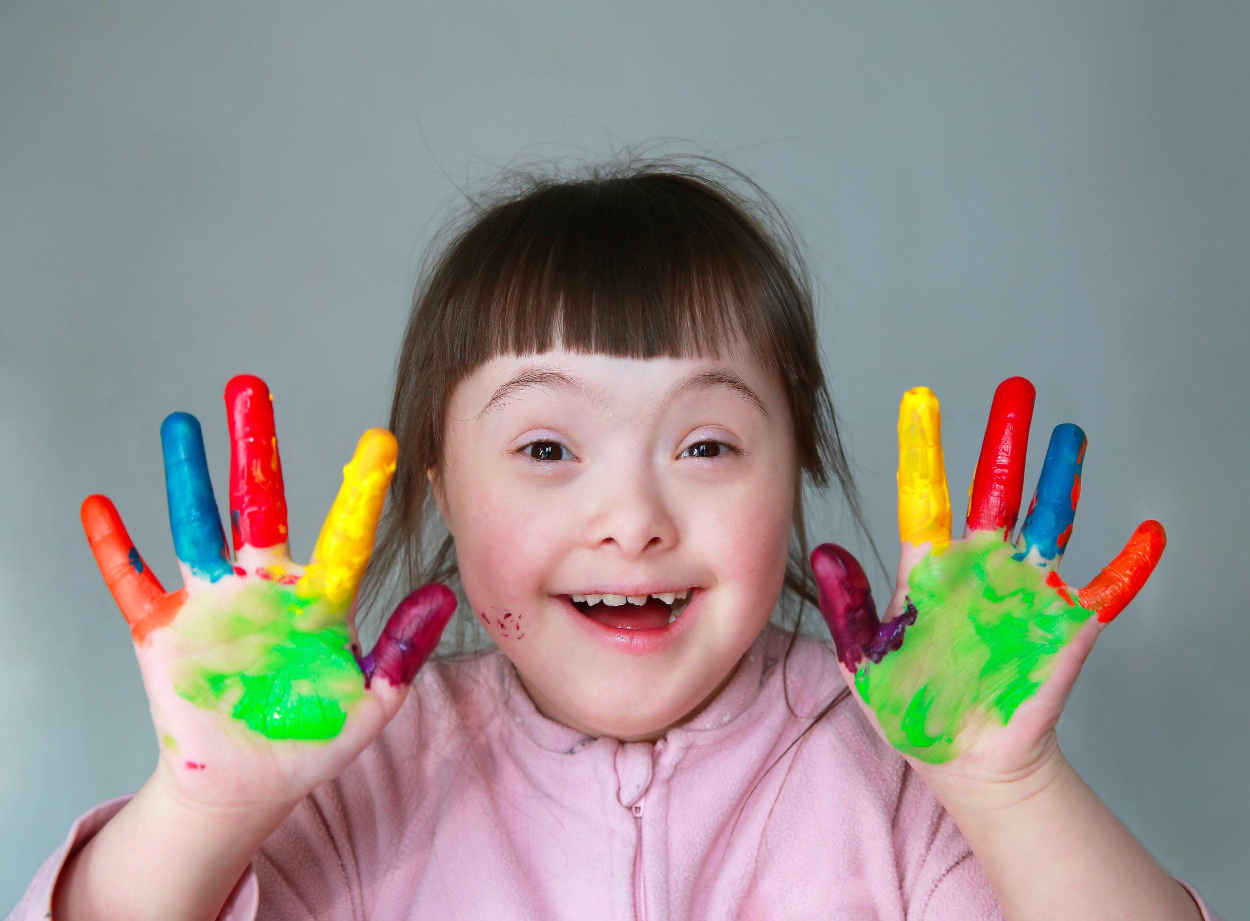 Cute little girl with painted hands. Isolated on grey background.